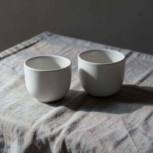 Two white ceramic cups resting on linen